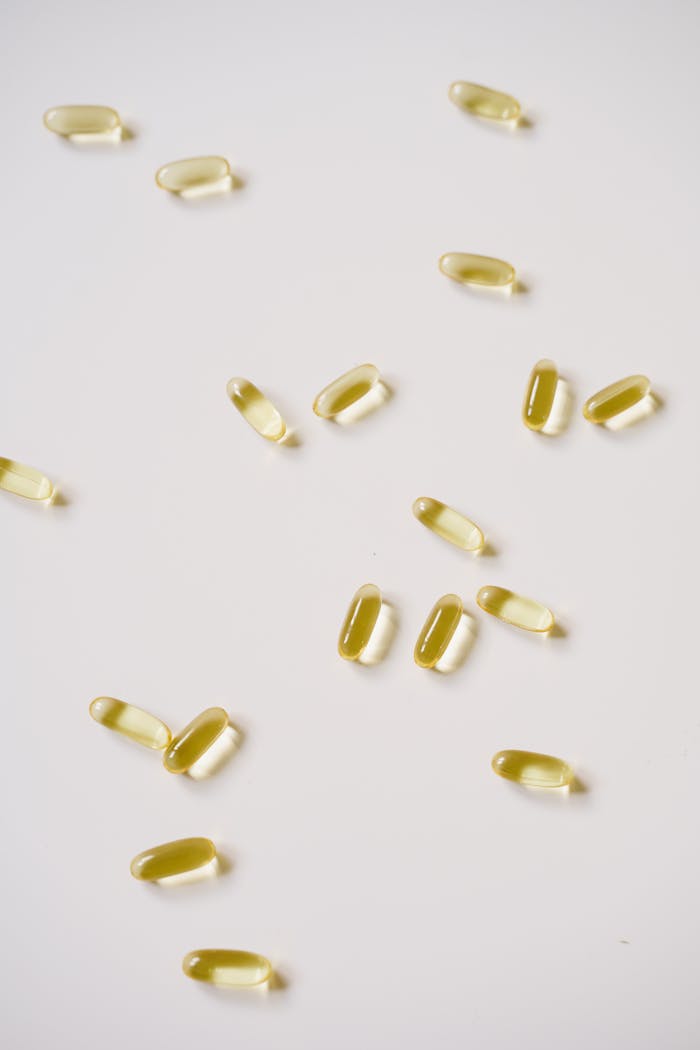 Close-up of yellow soft gel capsules scattered on a white background, perfect for pharmaceutical themes.